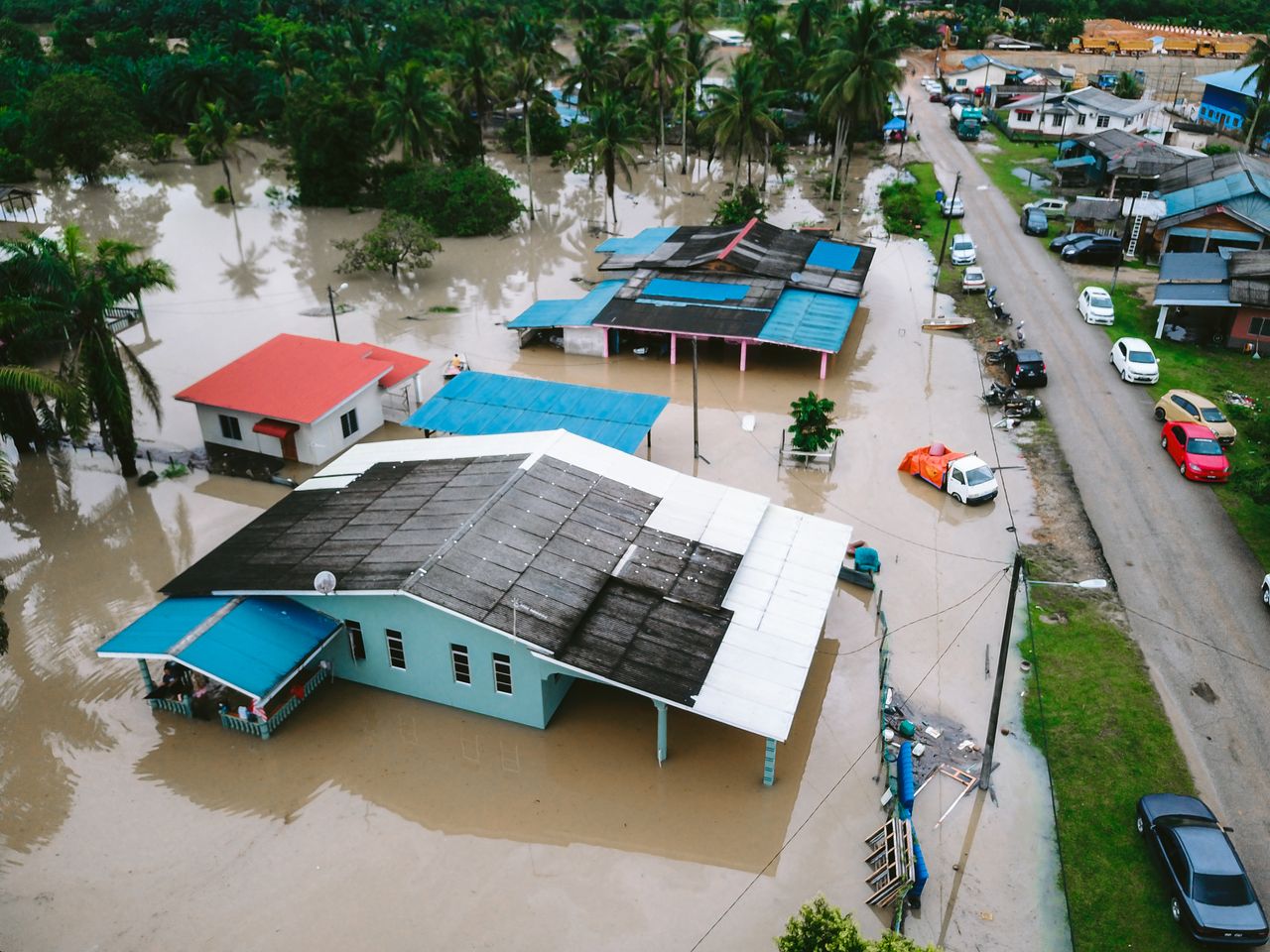 Services Aerial view of a flooded village in Kijal, Terengganu, Malaysia, showcasing submerged houses and streets.